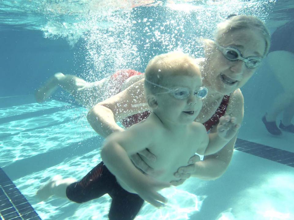 Swim Instructor and Young Boy Swimming Under Water